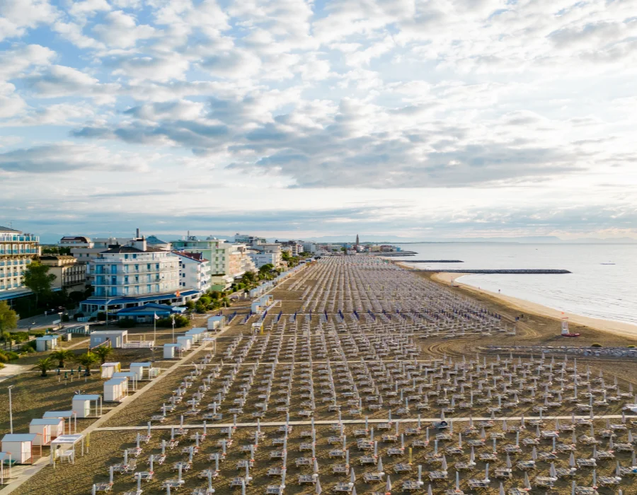 Panoramablick auf den Strand von Caorle mit Reihen von Sonnenschirmen und Meer während eines Sommerurlaubs